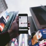 high angle photo of person holding turned on smartphone with tall buildings background